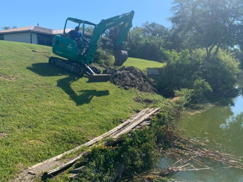 JChavez Flower Mound Tree Service 7 Mini excavator clearing vegetation along a pond bank