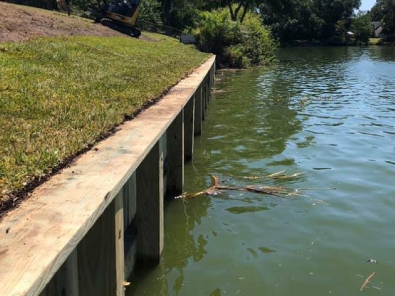 JChavez Flower Mound Tree Service 6 Retaining wall along a grassy pond bank